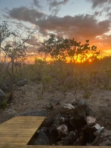 un tramonto su un campo con una passerella di legno di Chalé cabana de ferro a Alto Paraíso de Goiás