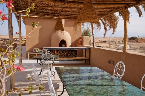 an outdoor patio with a table and chairs and a fireplace at Agafay Desert Hotel in El Karia