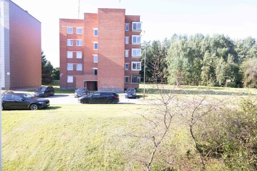 a parking lot with cars parked in front of a building at Močiutės apartamentai in Anykščiai