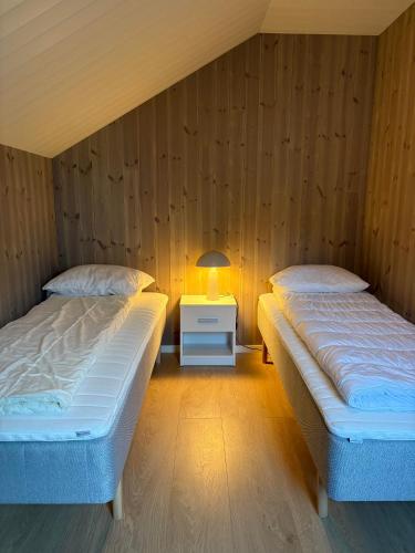two beds in a room with a lamp on a night stand at Finnvika Panorama, Stamsund - Lofoten in Stamsund