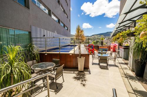 a balcony with tables and chairs on a building at IT Itabira Hotel in Itabira