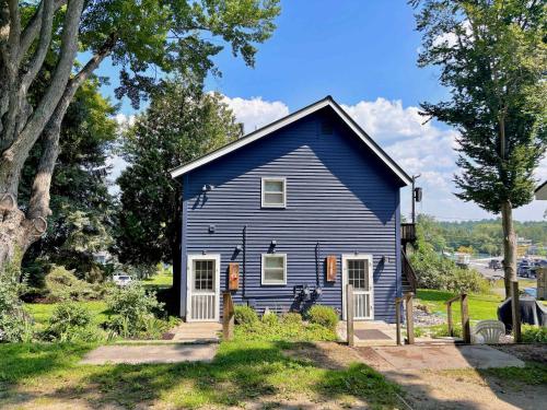 a blue house in a yard with trees at Cozy Main Level Torch Lake Stay with Private Entry & Fire Pit in Rapid City