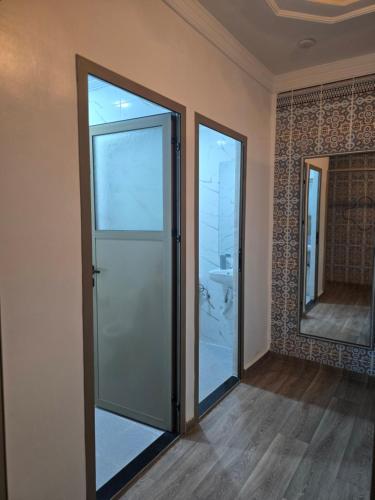 an empty room with a glass door and a mirror at Narjiss Hostel in Fès
