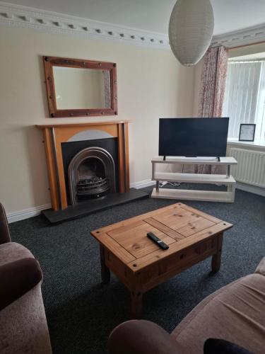 a living room with a coffee table and a fireplace at Arthur house in Whitehouse Lower