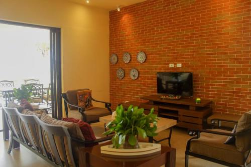 a living room with a tv and a brick wall at Casa Bul-Kay's in Chicxulub