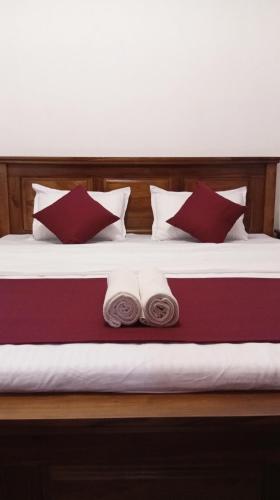 a bed with red and white pillows and towels at Ella Sunrise Villa in Ella