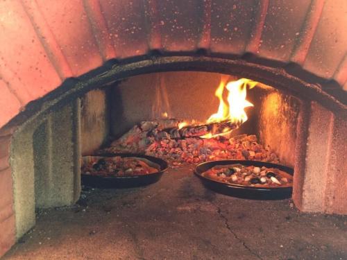 three pans of food in a brick oven at La Ferme in Barberêche