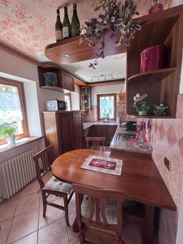 a kitchen with a wooden table with chairs and wine bottles at Appartamento Tudaio in Laggio