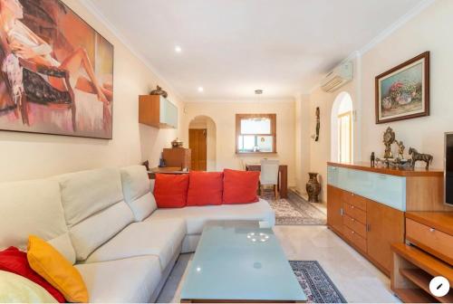 a living room with a white couch and red pillows at Piso bonito cerca de la playa con piscina, jardín, gimnasio y garaje in Jávea