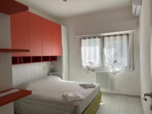 a bedroom with a bed with red cabinets and a window at barchetta in Modena