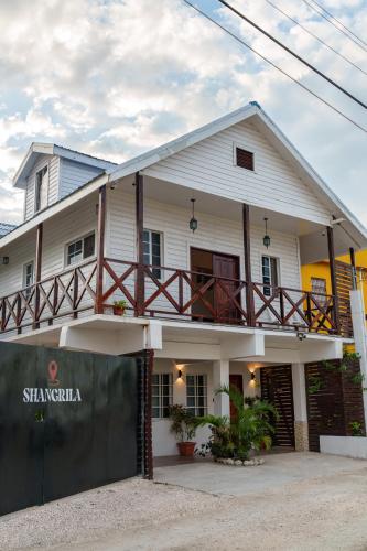 a white house with a fence in front of it at Casa De Shangrila in Belize City
