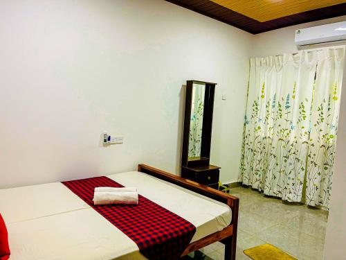 a bedroom with a bed with a red checkered blanket at Sigiri Pandora Lodge & Hostel in Sigiriya
