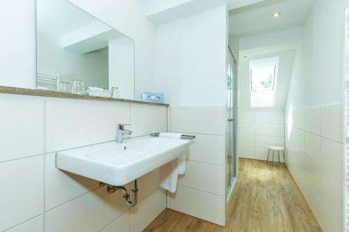 a white bathroom with a sink and a mirror at Hotel Zum Forst in Kranzberg