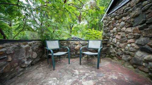 twee stoelen voor een stenen muur bij 3-Bedroom Cottage #1 Hamilton in Sharbot Lake