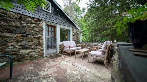 een stenen huis met 2 stoelen en een tafel bij 3-Bedroom Cottage #1 Hamilton in Sharbot Lake