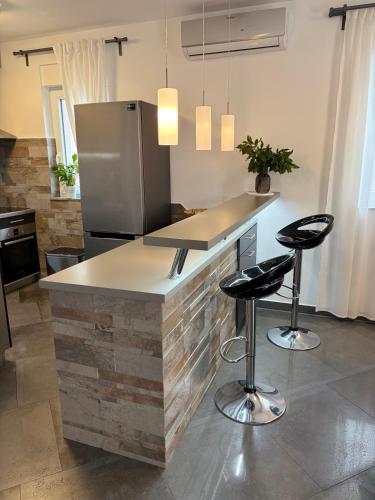 a kitchen with a counter with a refrigerator and stools at Villa Silver Novigrad with private pool in Novigrad Istria