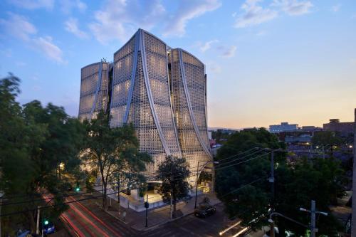 a tall building with mirrored windows in a city at Xoma by Viadora in Mexico City