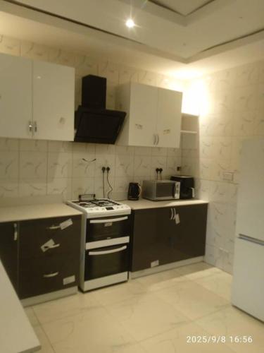 a kitchen with white cabinets and a stove top oven at Cutting Edge Guest House in Daranka