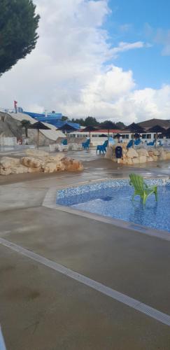 a pool at a resort with blue chairs and tables at Très beau Mobil Home 40 m2 3Ch - Camping 4 étoiles Les Charmettes 370- proche FUN ZONE in Les Mathes