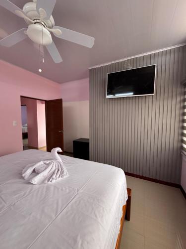 a white swan laying on a bed with a ceiling fan at BeachClub Tonsupa by Cascada Spa Ecuador in Tonsupa