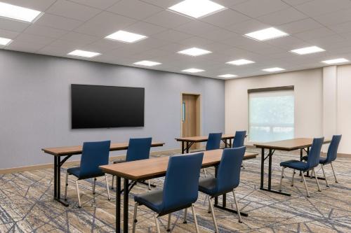 a conference room with tables and chairs and a screen at Holiday Inn Express & Suites Pittsfield-Lenox-Berkshires by IHG in Pittsfield