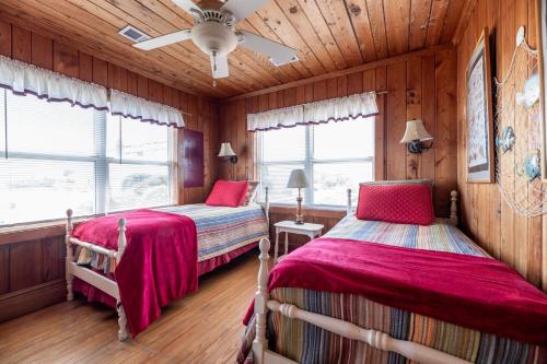 two beds in a room with wooden walls at Mitch's Haven in Kitty Hawk