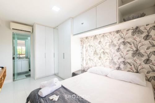 a bedroom with a large white bed with a floral wallpaper at Apto 2 quartos c vista pro parque na Praia JSM0103 in Salvador