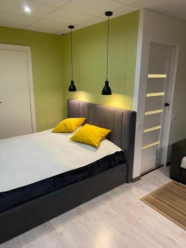 a bedroom with a bed with two yellow pillows at Reiņu meža Apartaments in Liepāja