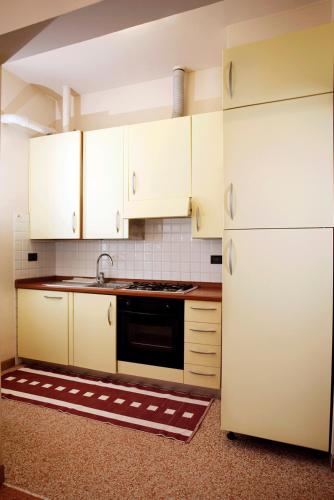 a kitchen with white cabinets and a sink and a refrigerator at Hotel Dei Fiori Restaurant - Meeting & Spa in Alassio