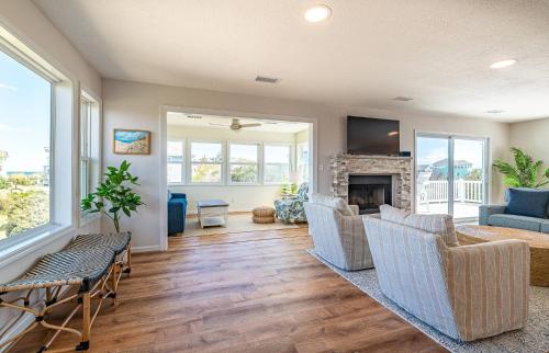 a living room with chairs and a fireplace at MoonDance OBX - D3135 in Port Trinitie