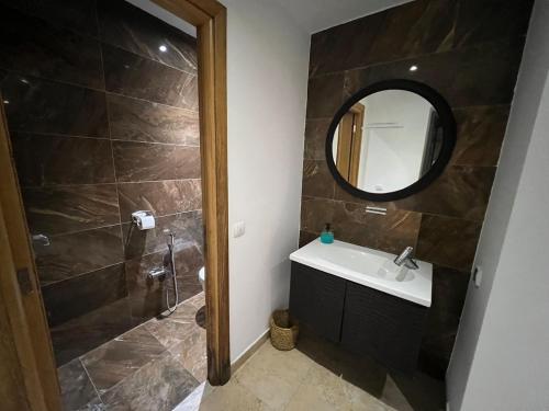 a bathroom with a sink and a mirror at Mahdia with sea view in Hiboun