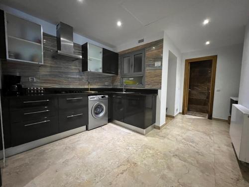 a kitchen with black cabinets and a washing machine at Mahdia with sea view in Hiboun