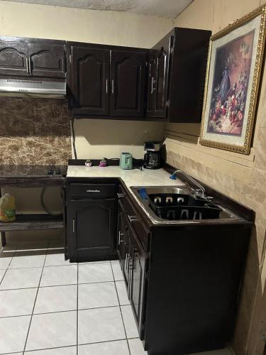 a kitchen with black cabinets and a sink at Spacious Apartment Great Location in Matamoros in Matamoros