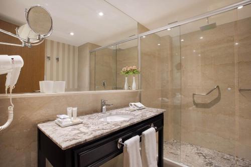 a bathroom with a sink and a glass shower at Windsor Plaza Brasilia in Brasilia