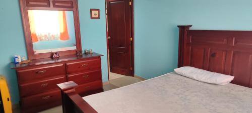 a bedroom with a bed and a dresser and a mirror at Los Tres Ojos Stay in Ensanche Savica de Mendoza