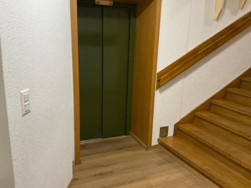 a hallway with a green door and stairs at BERNA,Signau XXL in Signau