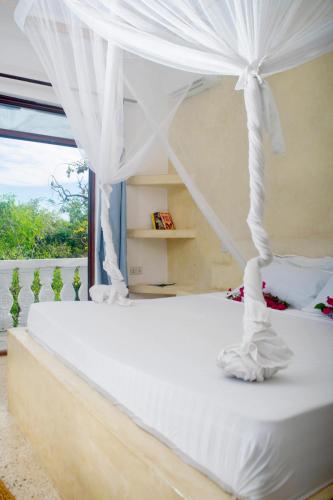Un dormitorio con una cama blanca con dosel. en Low budget suite in Paje, en Paje