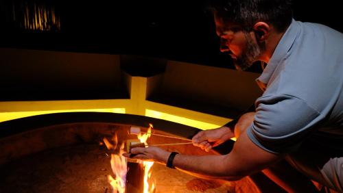 a man is standing next to a fire oven at Mologa River Lodge in Rust de Winter