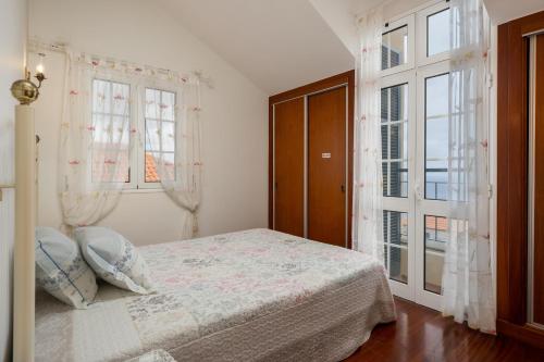 a bedroom with a bed and two windows at Casa da Avo in Faial