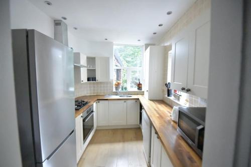a kitchen with white cabinets and a stainless steel refrigerator at Charming & Cosy Home Stockport in Stockport