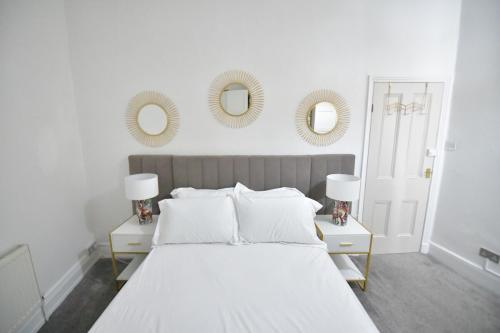 a white bedroom with a large bed and two mirrors at Charming & Cosy Home Stockport in Stockport