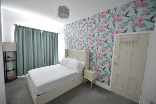 a bedroom with a bed and a floral wallpaper at Charming & Cosy Home Stockport in Stockport
