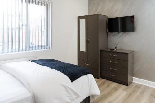a bedroom with a bed and a dresser with a television at Spacious En-Suite Double Room near Coventry Uni & Hospital in Wyken