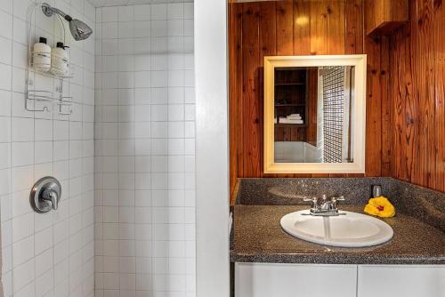 a bathroom with a sink and a mirror and a shower at Orchid Hale in Kailua-Kona