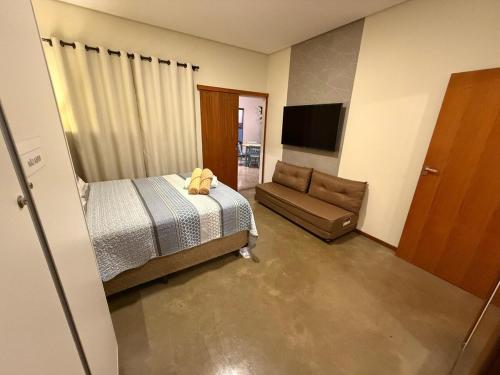 a bedroom with a bed and a couch and a television at Casa Jatobá e SPA in Alto Paraíso de Goiás
