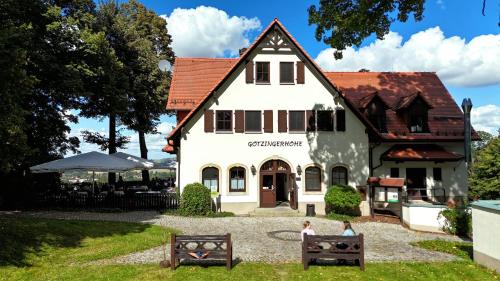 a white house with two people standing in front of it at Berggasthof & Hotel Götzinger Höhe in Neustadt in Sachsen