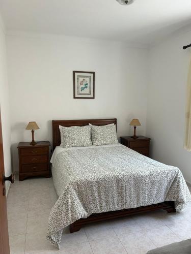 a bedroom with a bed with two nightstands and two lamps at Casa Reis in Odeceixe
