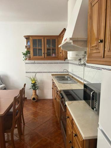 a kitchen with wooden cabinets and a sink and a table at Casa Reis in Odeceixe