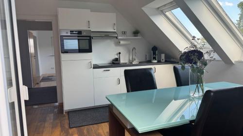 une cuisine avec des armoires blanches et une table en verre dans l'établissement Apartment Köln Bonn DeLux Burgblick, à Bornheim
