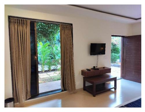 a living room with a large window and a table at Pegasus Lifestyle Resort Karjat in Karjat